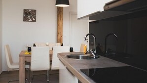 A modern kitchen with a black countertop, stainless steel sink, and a wooden ceiling beam.