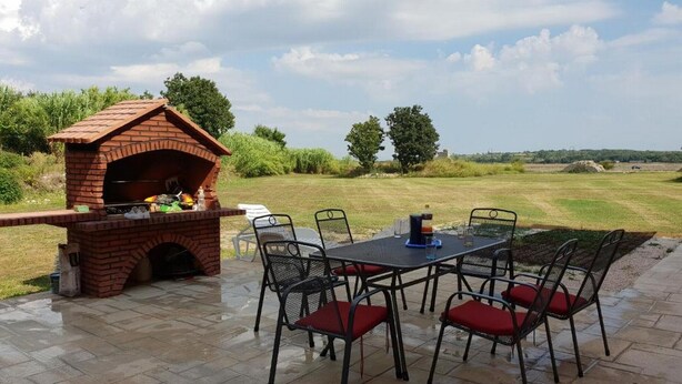 Un patio al aire libre con una parrilla de ladrillo y una mesa con sillas.