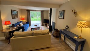 Una sala de estar con sofá, mesa de centro, televisor, chimenea y mesa de comedor.