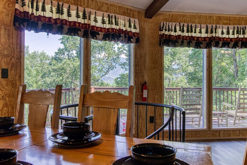 Interior de madera con ventanas amplias que dan a una terraza y árboles.