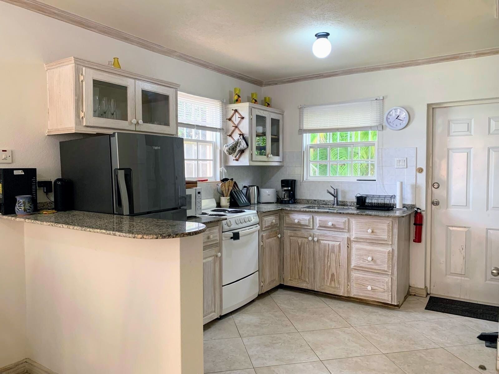 A kitchen with white cabinets, a refrigerator, a stove, and a sink.