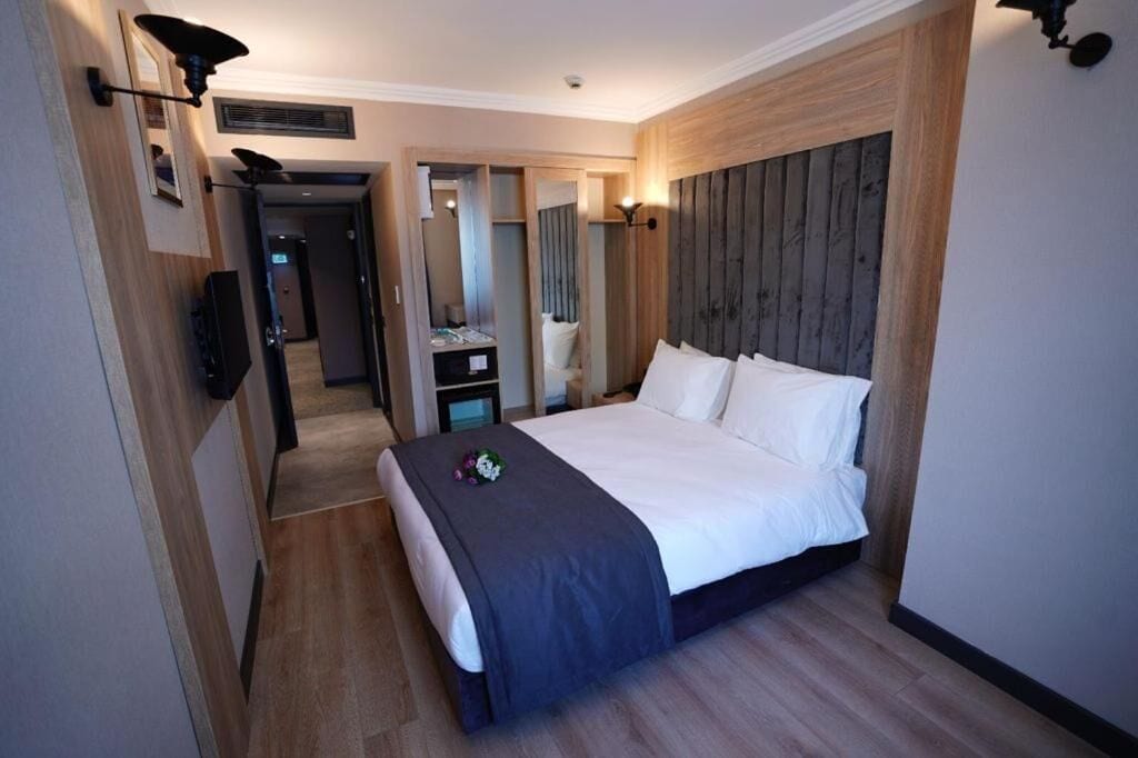 Ein Hotelzimmer mit einem großen Bett, einem Fernseher, einem Schreibtisch und einem Spiegel.