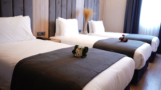 Quarto de hotel com duas camas, cada uma com roupa de cama branca e cabeceiras escuras.