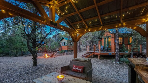 A covered outdoor area with a fire pit, seating, and string lights. - Live Simply Cabin | Glamping at it's finest (Orderville)