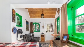A cozy room with a bed, a wooden dresser, a desk, and a green window. - Live Simply Cabin | Glamping at it's finest (Orderville)