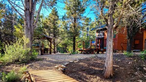 A wooden deck leading to a rustic cabin with a covered outdoor seating area. - Live Simply Cabin | Glamping at it's finest (Orderville)