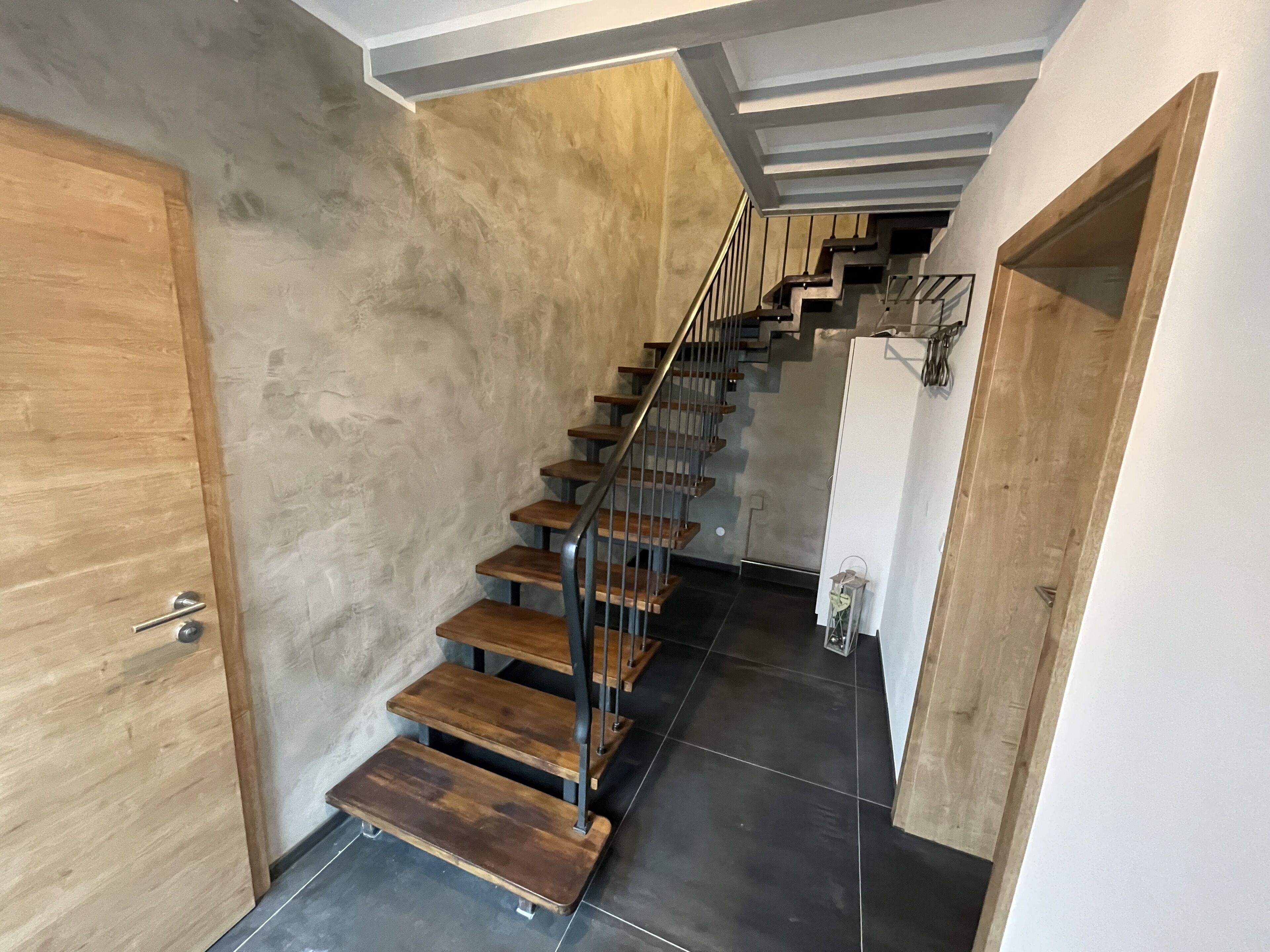 Eine Treppe mit Holzdielen und Metallgeländern, die zu einer oberen Etage führt.