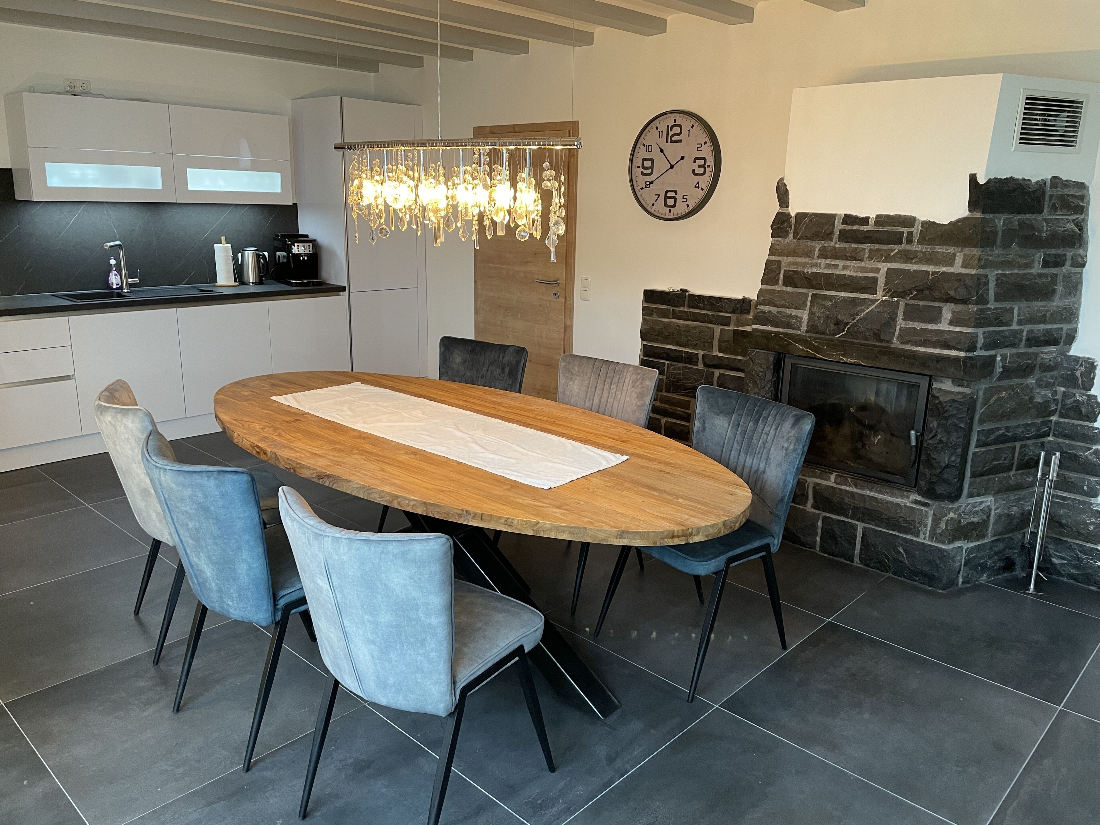 Une cuisine moderne équipée d’une cuisinière intégrée, d’une table à manger avec des chaises et d’une horloge murale.