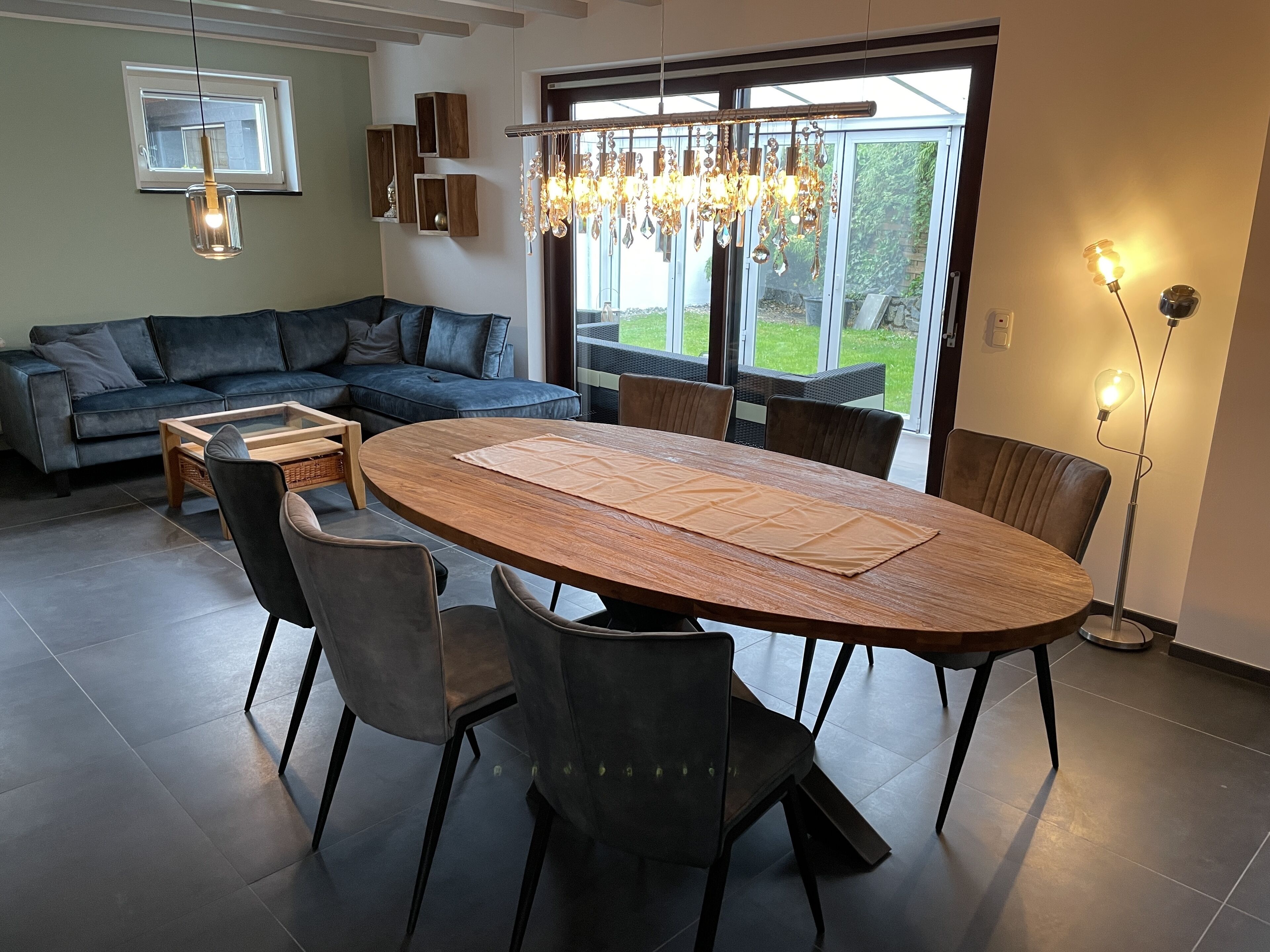 Ein modernes Wohnzimmer mit einem großen runden Tisch, dunklen Sofas und einer Chandelier.
