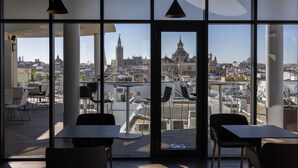 Un restaurante con vistas a un paisaje urbano histórico, que incluye una catedral y torre destacadas.
