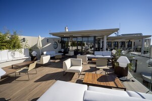 Una terraza en la azotea con mobiliario exterior, un espacio cubierto y vistas del horizonte de la ciudad.