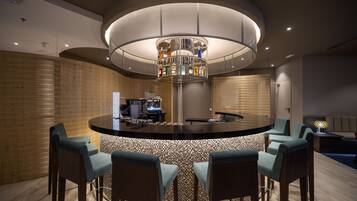 Een moderne bar met een ronde bar, barstoelen en een bijzondere hanglamp.