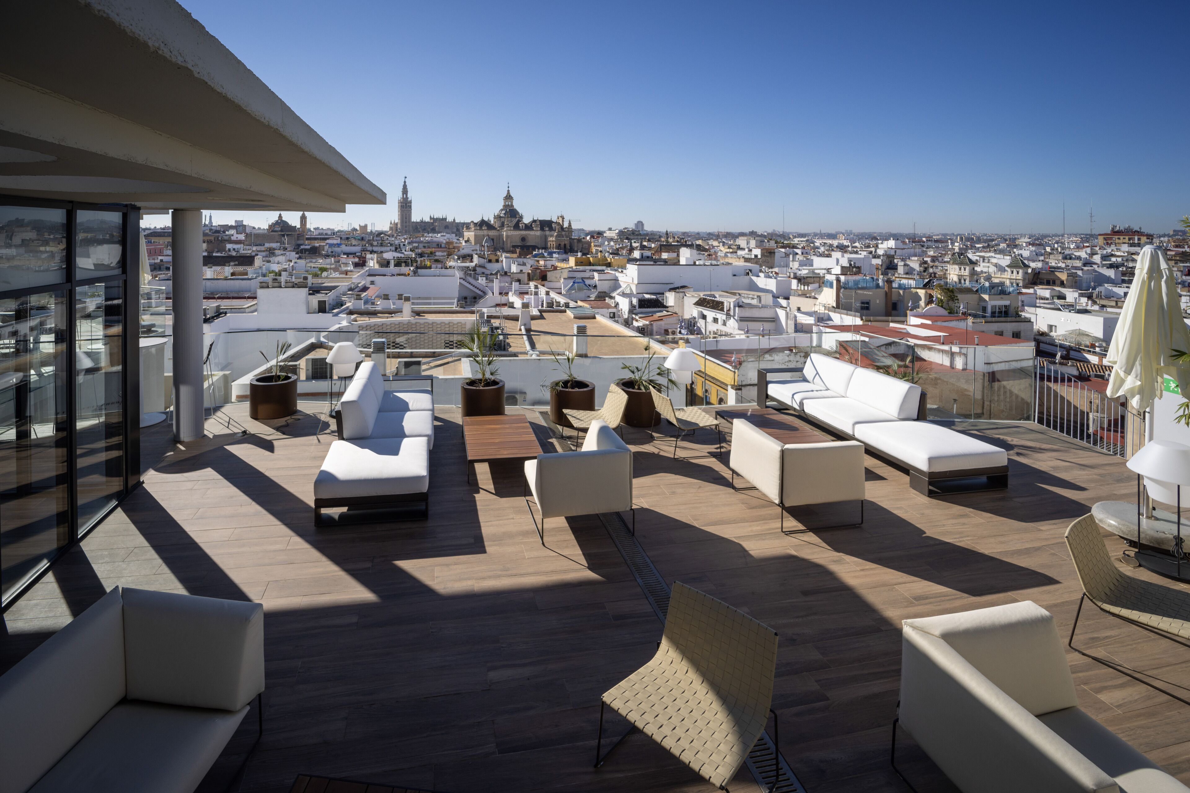 A rooftop terrace with outdoor seating, potted plants, and a view of the cityscape.