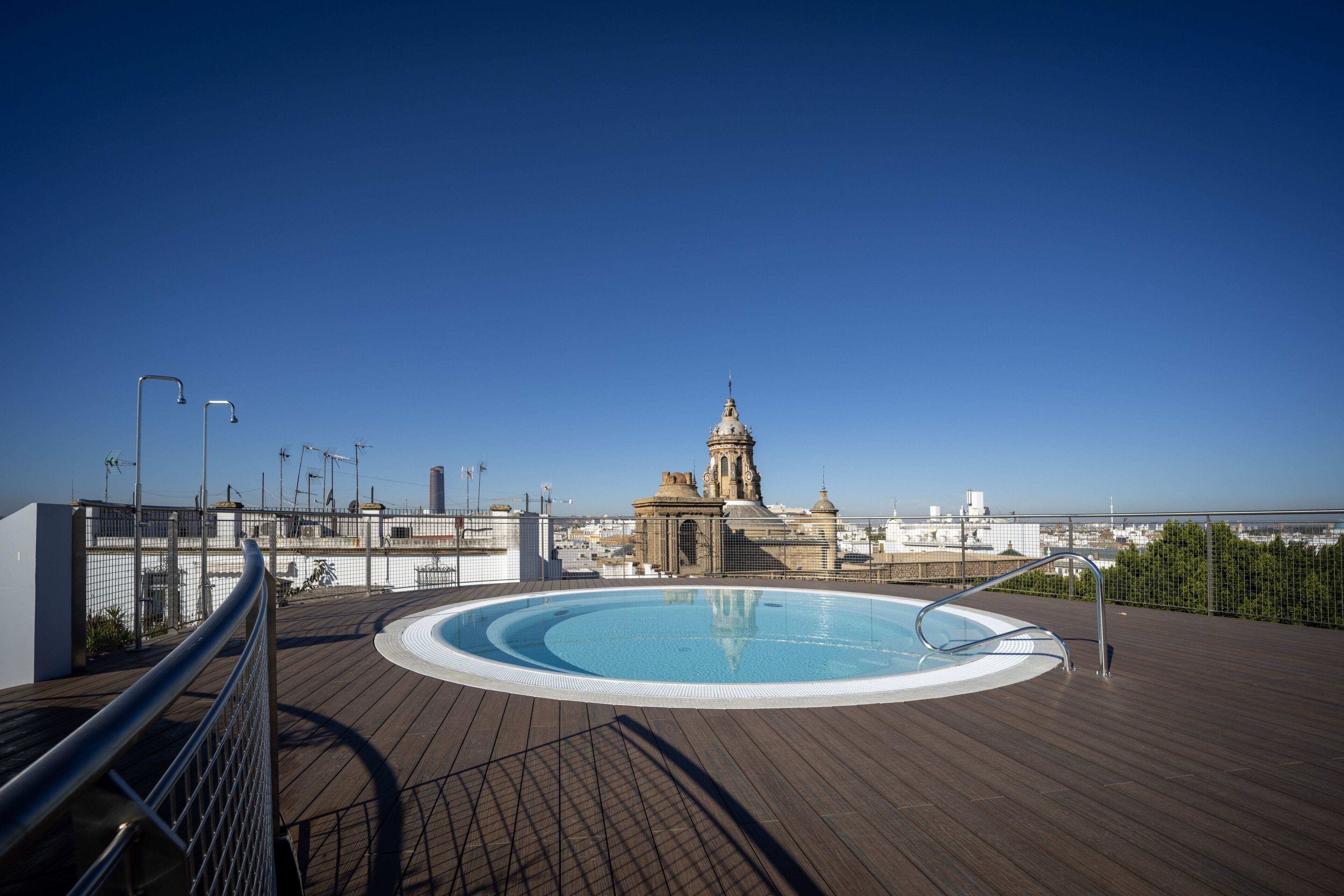 Una piscina en la azotea con vistas a un edificio histórico al fondo.
