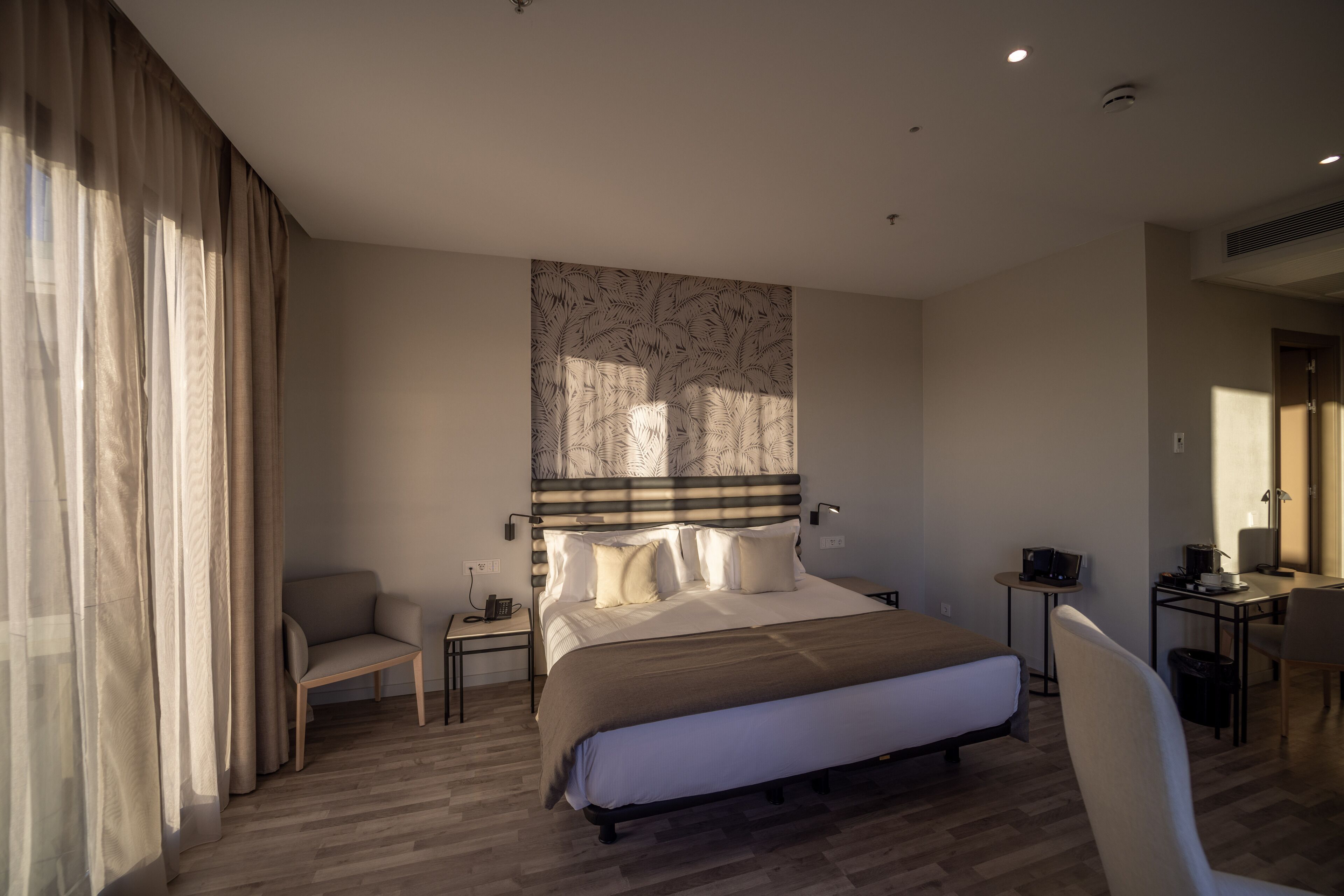 Ein modernes Hotelzimmer mit einem großen Bett, einem Schreibtisch, einem Sessel und einer Couch.