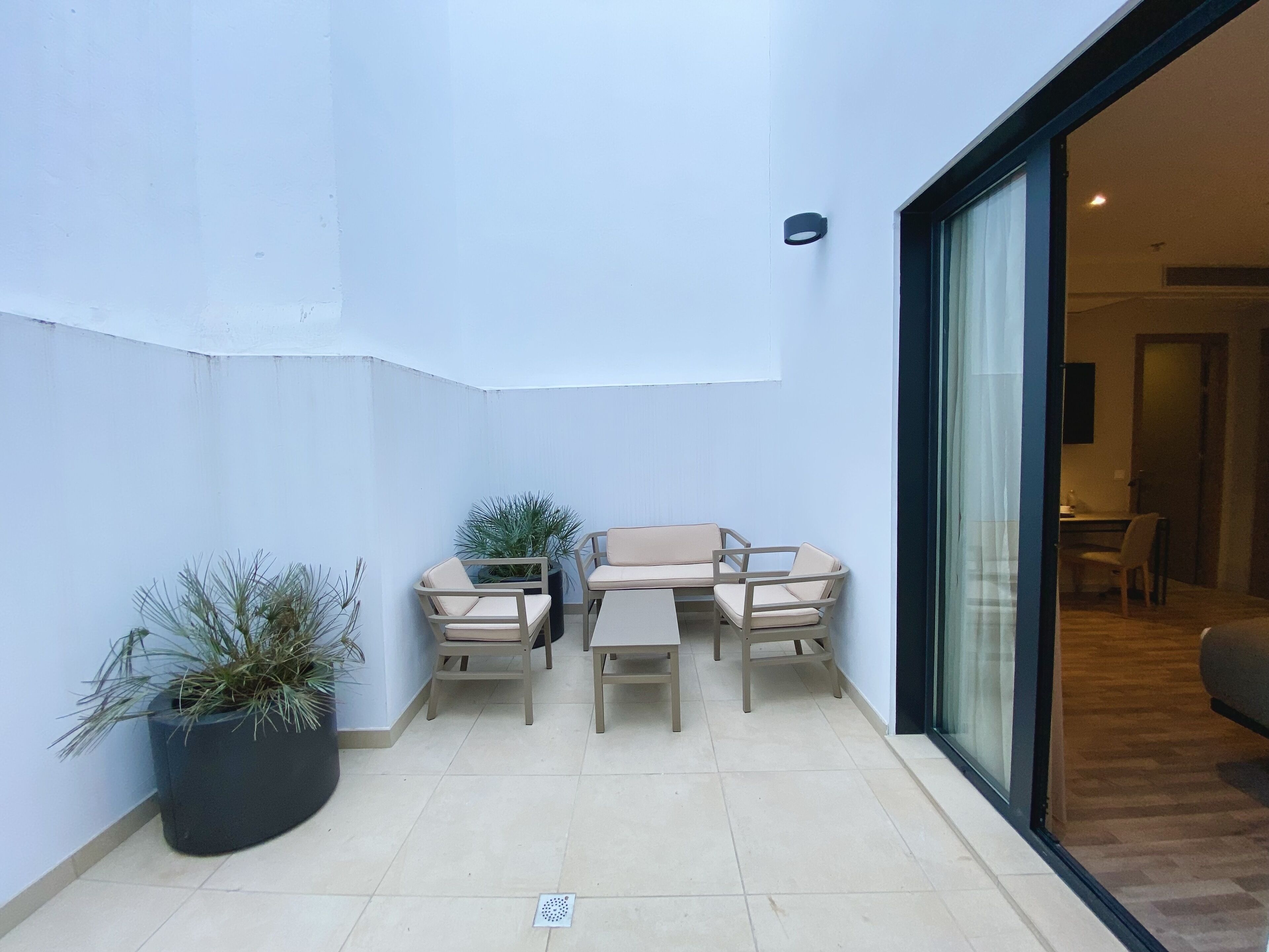 A small patio area with a sofa set and a potted plant.
