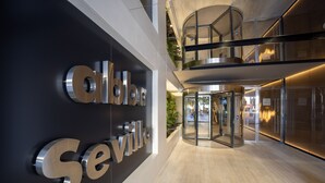 Une entrée d’hôtel moderne avec une porte tournante et une enseigne indiquant « Séville ».