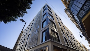 Un edificio moderno de varios pisos con grandes ventanales y una entrada en esquina.
