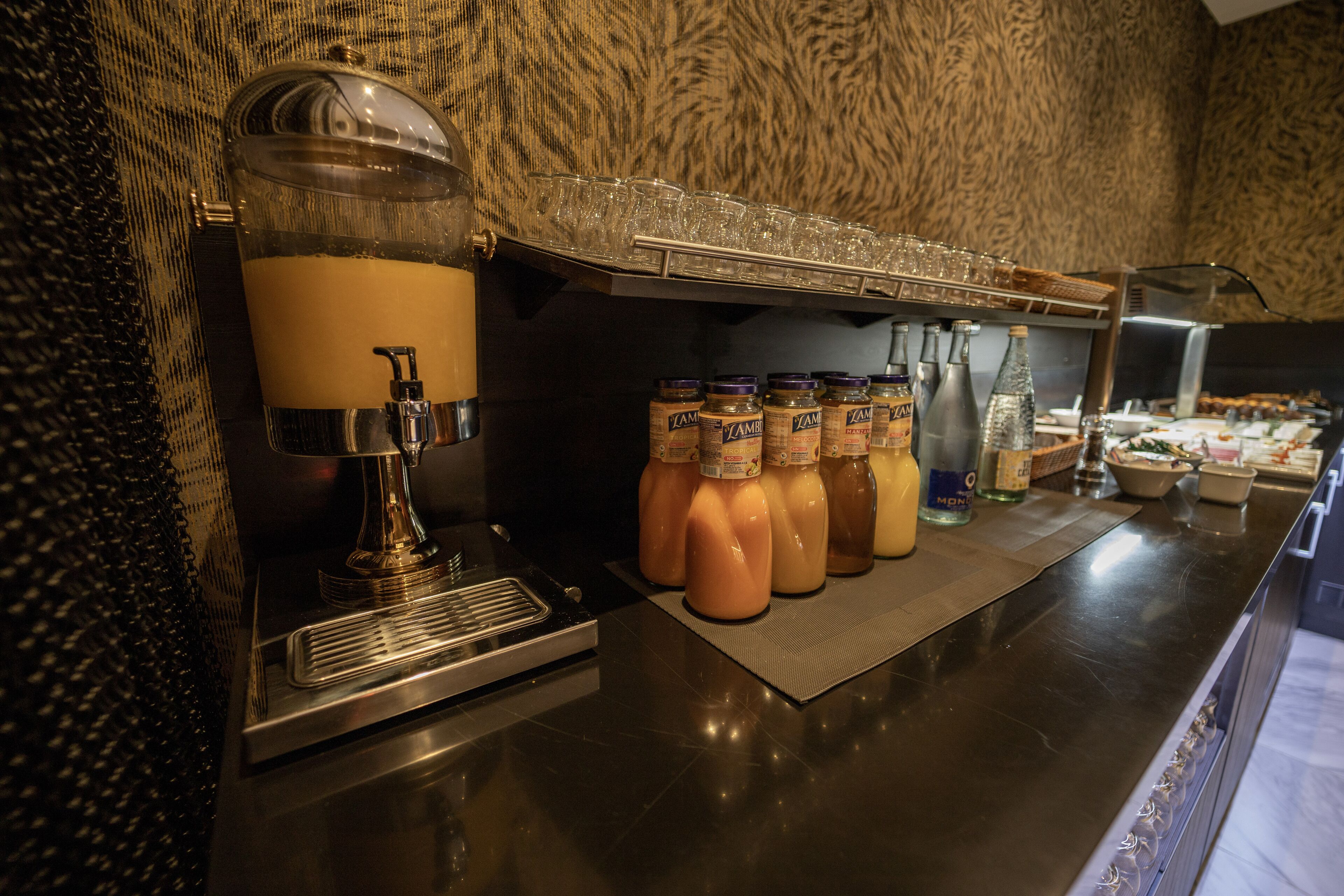 A beverage station with a coffee machine, a milk dispenser, and several bottles of milk and other beverages.