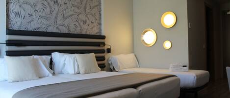 A hotel room with two beds, a patterned wallpaper, and a wall-mounted light fixture.