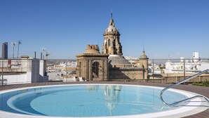 Una piscina en la azotea con vistas a un edificio histórico con cúpulas y aguja.