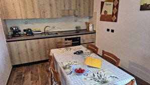 Cocina compacta con armarios de madera, un lavamanos integrado y una zona de comedor con una mesa dispuesta para cuatro.