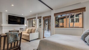 Un dormitorio con una cama grande, un sofá, un televisor montado en la pared y una ventana con vistas al exterior.