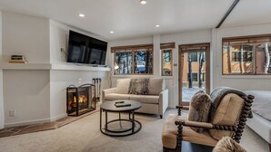 Una sala moderna con chimenea, un televisor de pantalla plana, un sofá y un sillón.