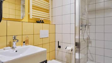 A bathroom with a white sink, toilet, and glass-enclosed shower.