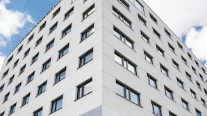 Un hotel moderno con entrada en esquina, ventanas amplias y fachada de vidrio reflectante.