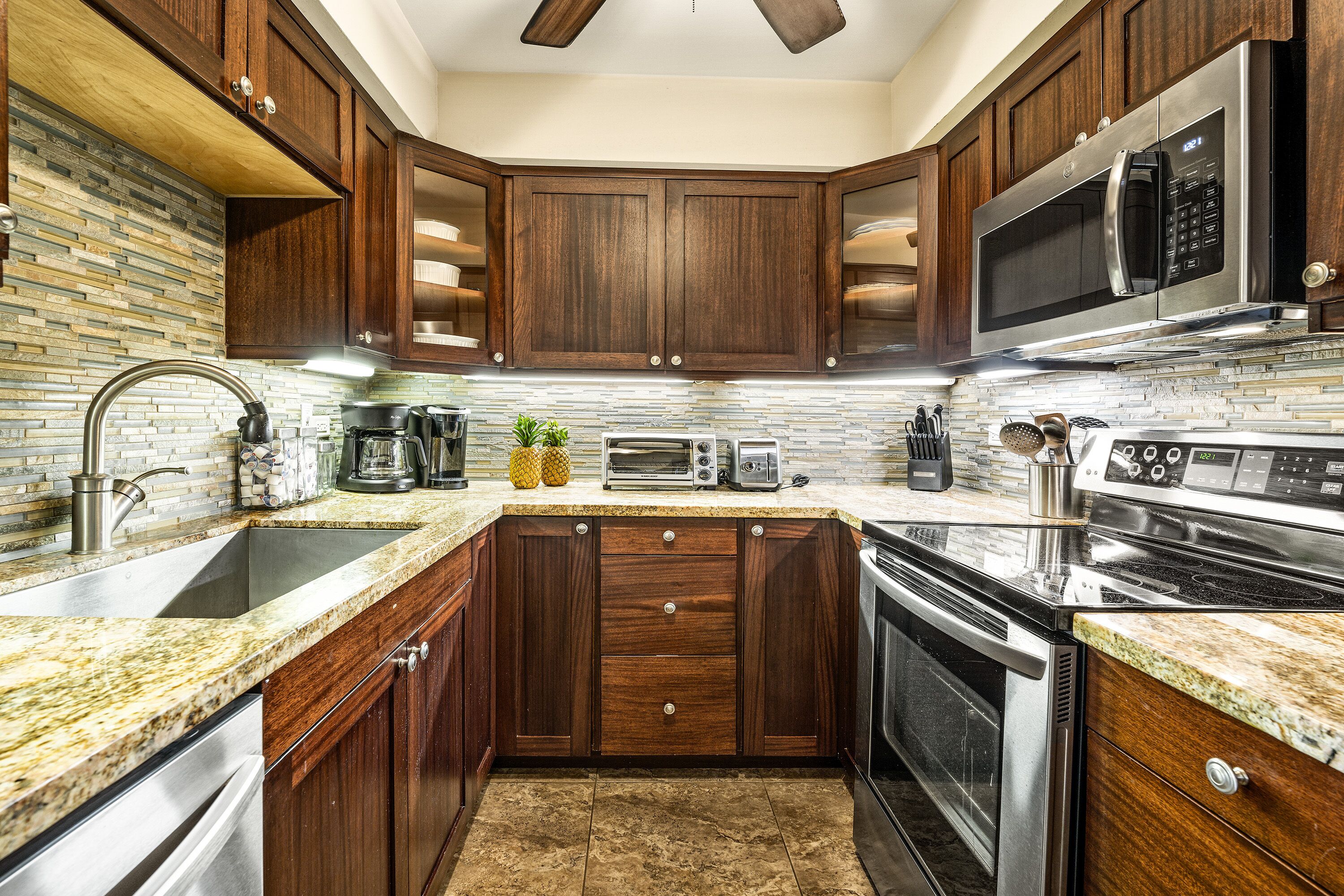 A modern kitchen with dark wood cabinets, stainless steel appliances, and a granite countertop.