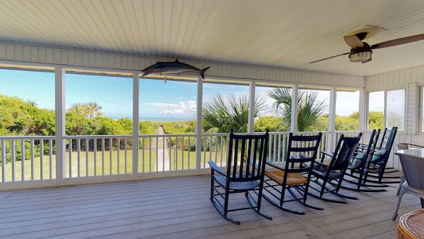 A covered outdoor area with a view of the ocean, wooden deck, rocking chairs, and a ceiling fan. - Bring your Family, Oceanfront, 8 bedroom, 4 bathroom, private boardwalk! (Isle of Palms)