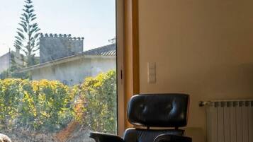 Una sala de estar moderna con un ventanal grande, un sillón de cuero, un sofá y una mesa de centro de madera.