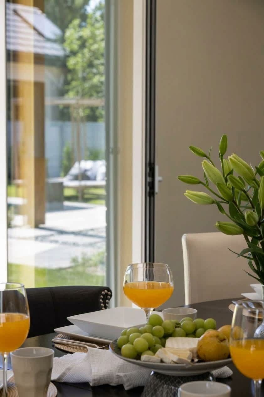 Et spisebord med en tallerken med frugt, en skål med ost og glas med appelsinjuice.