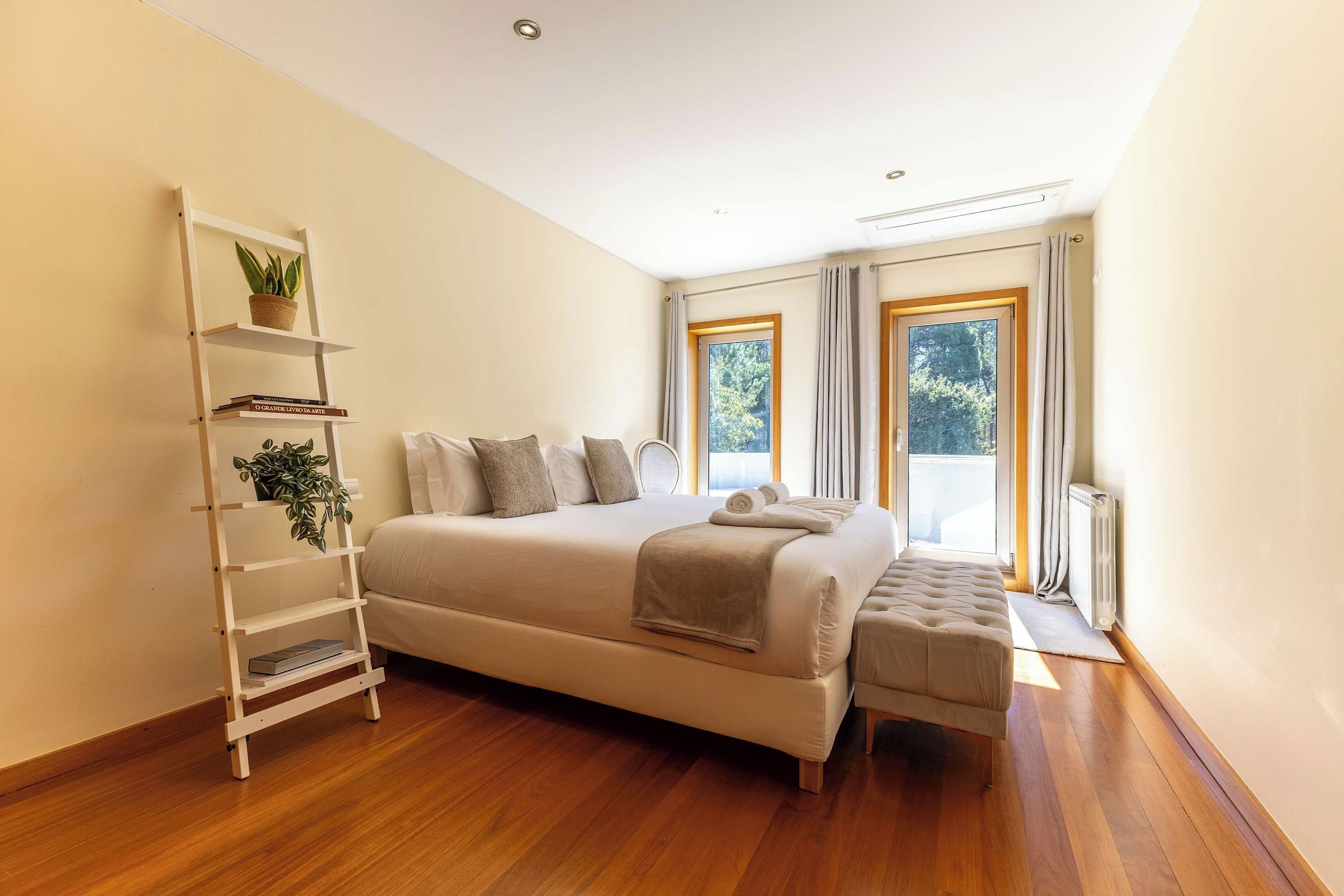 A bedroom with a large bed, a bedside table, a floor lamp, and a window with curtains.