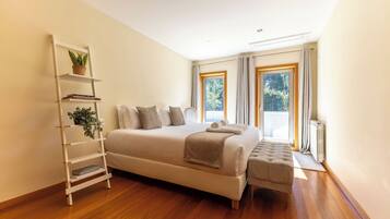 Un dormitorio con una cama grande, una mesita de noche, una lámpara de pie y una ventana con cortinas.