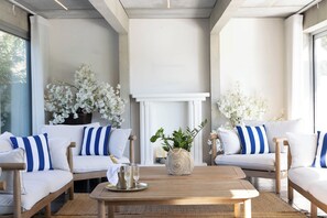 A modern lounge area with white sofas, blue striped cushions, and white flowers.