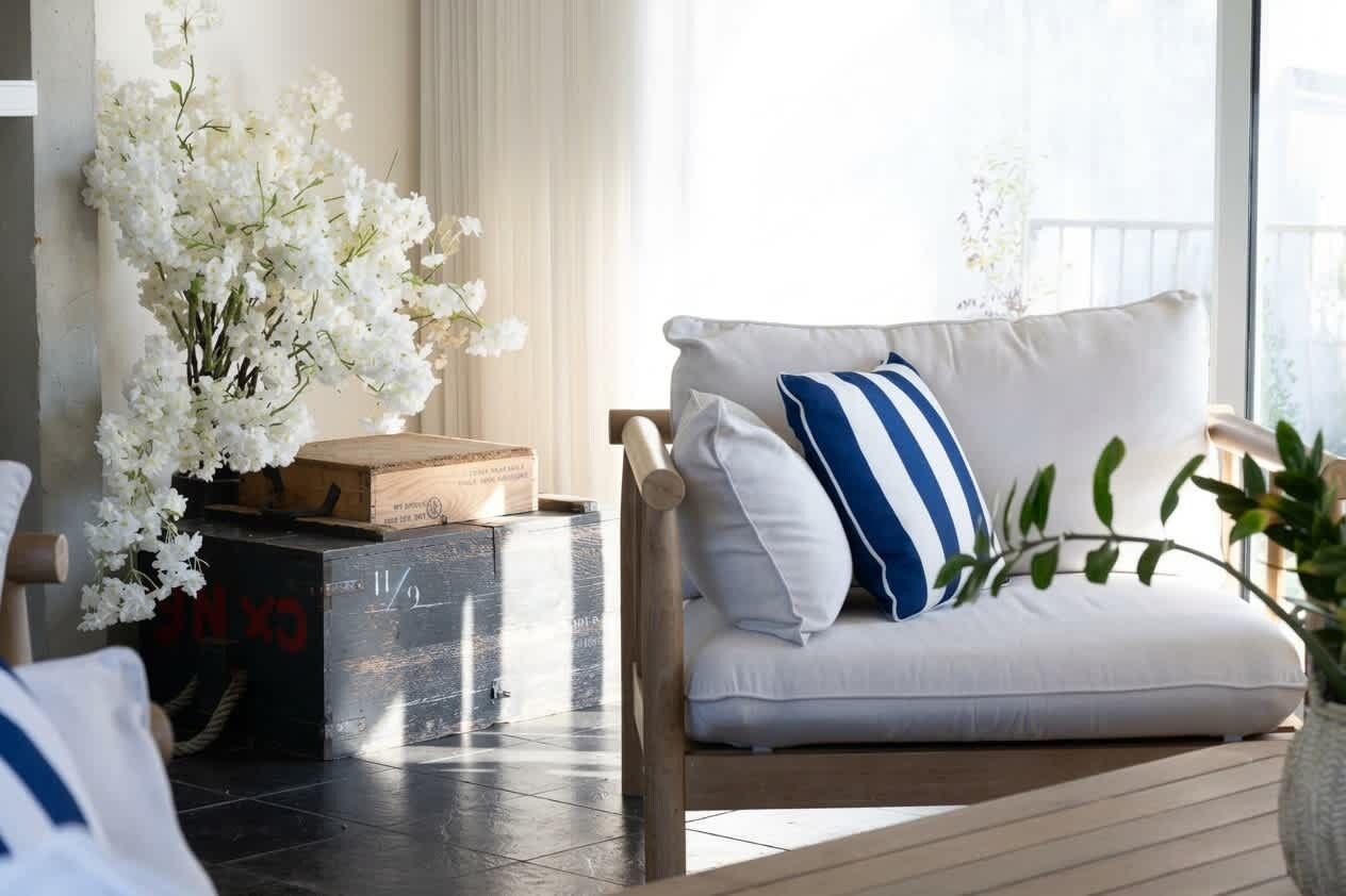 Una sala de estar moderna con un sofá blanco, un cojín azul y blanco a rayas y una mesa de centro de madera.