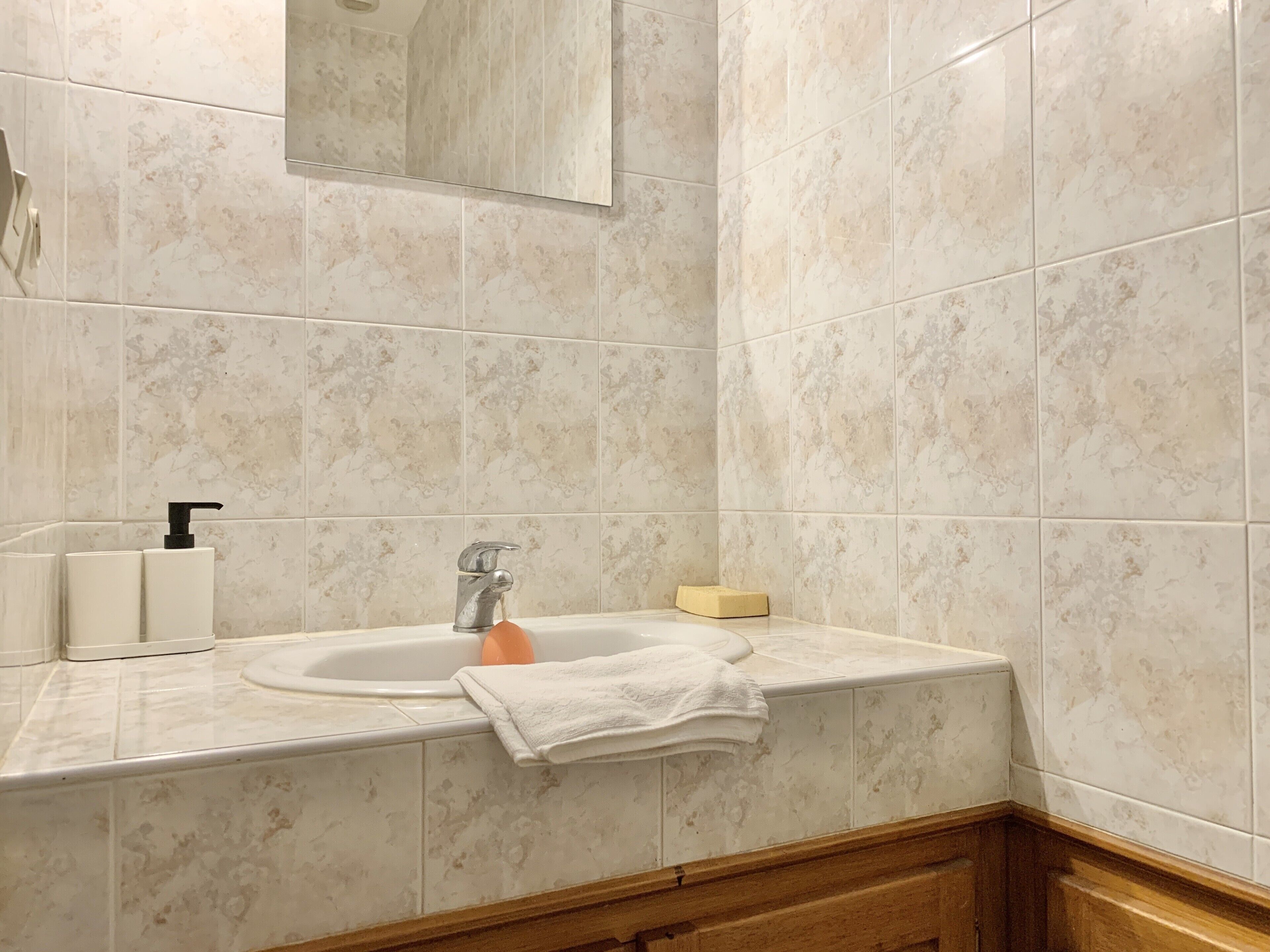 A bathroom with a sink, mirror, and toiletries.