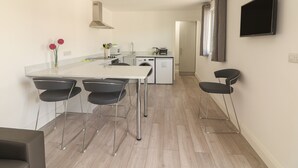 Een moderne keuken met een centraal eiland, barstoelen, een flatscreen televisie en een wasmachine.