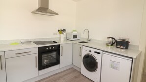 Een kleine keuken met een magnetron, broodrooster, spoelbak, oven en wasmachine.
