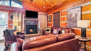 Una sala de estar acogedora con chimenea, sofá de cuero y una decoración de pared con motivos de osos.