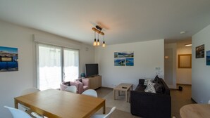 A modern living room with a wooden dining table, white chairs, a black sofa, and a TV. - La Douce Folie - Apartment for 4 to 5 people in Sevrier (Sévrier)