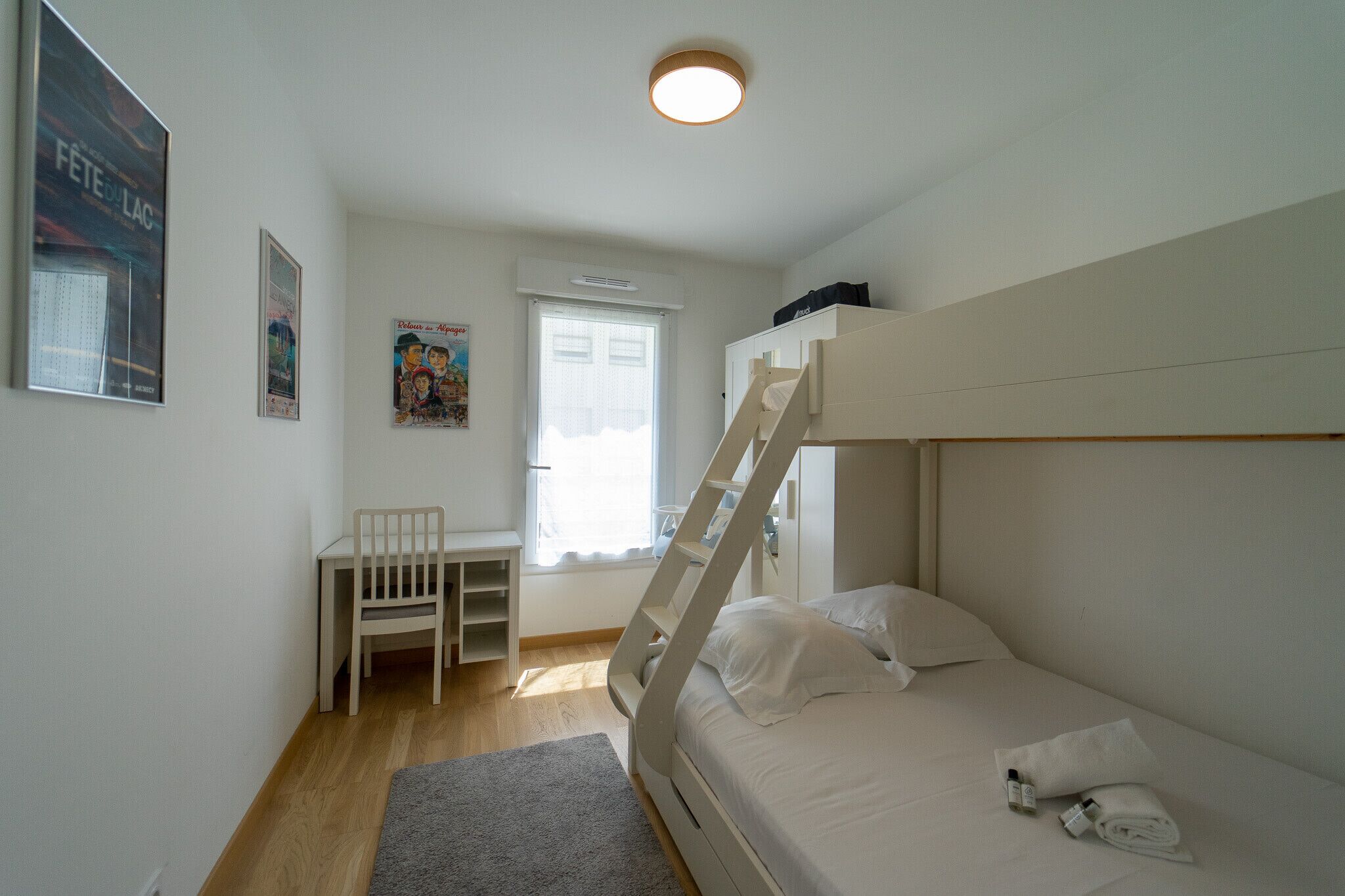Een slaapkamer met een stapelbed, een bureau en een stoel.