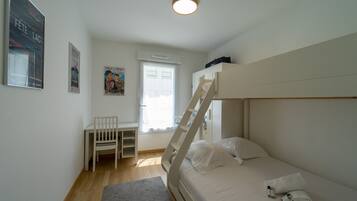 Een slaapkamer met een stapelbed, een bureau en een stoel.
