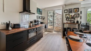 Una cocina moderna con encimera de madera, armarios negros y un ventanal con vistas a un balcón.