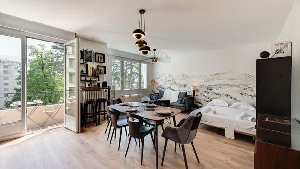 Una sala de estar moderna con comedor, una cama y un ventanal que ofrece vistas de la ciudad.