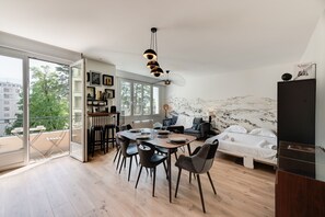 Una sala de estar moderna con comedor, una cama y un ventanal que ofrece vistas de la ciudad.