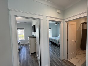 A hallway with a kitchen area, a bedroom with a bed, and a bathroom with a shower. - Custom 3BR 3BA with Private Pool & Elevator - new in 2022 (Sunset Beach)