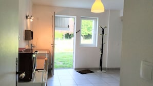 A modern kitchen with a built-in oven, a refrigerator, and a sink. There is a door leading to a balcony with a view of the outdoors.